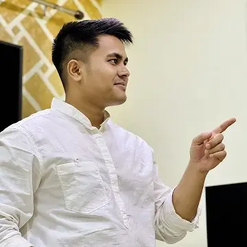 Man in white shirt pointing and smiling indoors